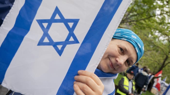 Une femme souriante derrière un drapeau israélien.