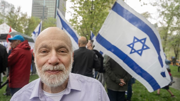 Plan rapproché de Dan Donath, avec en arrière de lui un drapeau d'Israël.