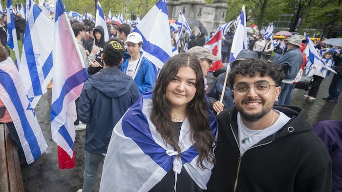 Une femme portant un drapeau israélien sur les épaules est souriante à côté d'un jeune homme.