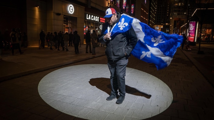 Une personne avec un drapeau du Québec sur le dos.