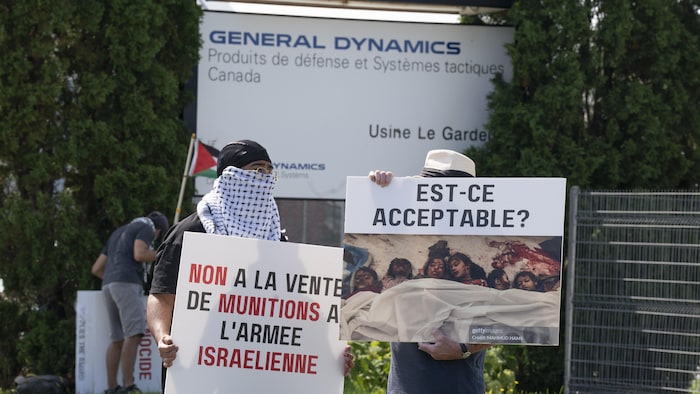 Des manifestants respectent des pancartes et un drapeau palestinien devant une usine de General Dynamics.