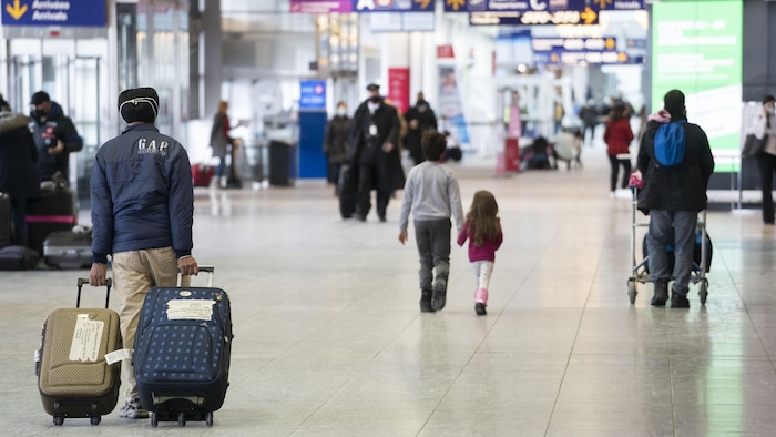 Des voyageurs transportant leurs valises à l'aéroport.