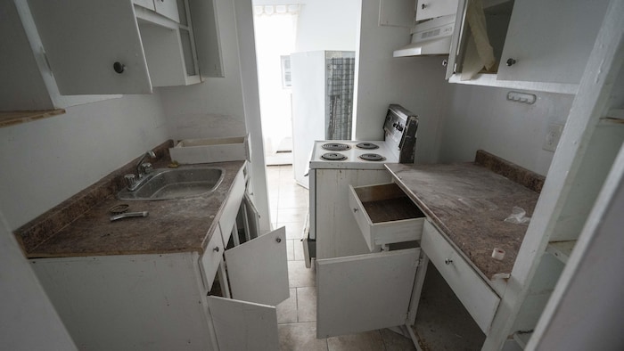 Un lavabo sale et un poêle dans la cuisine d'un logement insalubre.