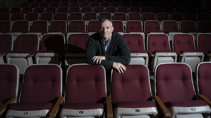 Joël Beddows assis sur un siège de théâtre.