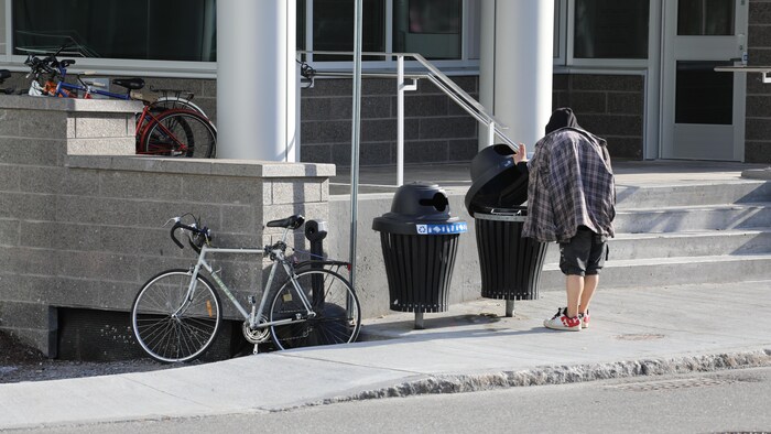 Un homme fouille à l’intérieur d’une poubelle située devant le centre d’accueil Lauberivière.