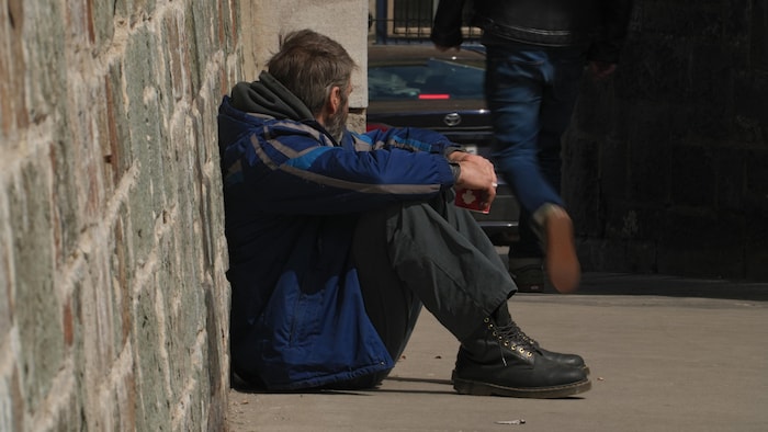Un homme est assis seul sur un trottoir.