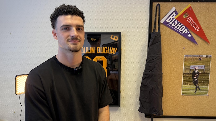 Nicolas Rioux pose pour la caméra devant un chandail de football.
