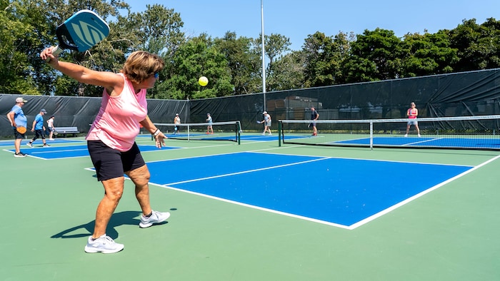 Une joueuse de pickleball qui frappe une balle.
