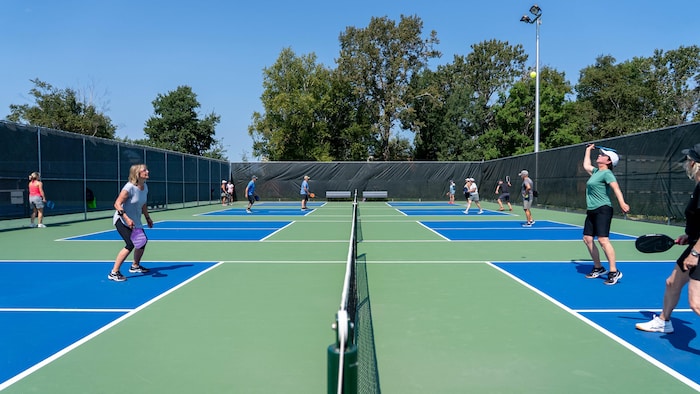 Vue sur plusieurs terrains de pickleball avec des joueurs qui s'envoient la balle.