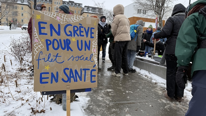 Une affiche de fabrication artisanale sur une ligne de piquetage devant l'Université du Québec à Rimouski.