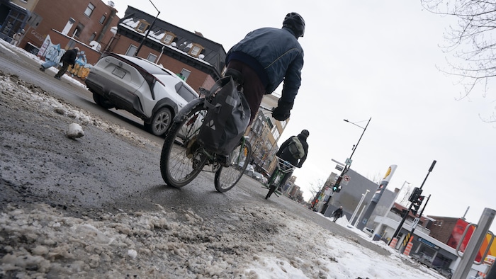Un cycliste montréalais circule sur une piste cyclable enneigée en février.