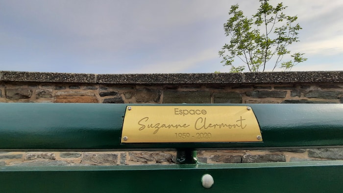 Une plaque dorée portant l'inscription «Espace Suzanne-Clermont» est installée sur un banc