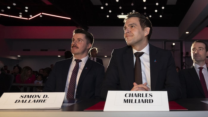 Charles Milliard est assis à une table.