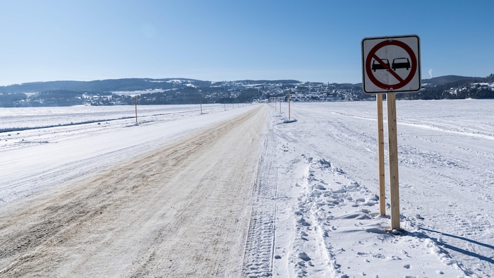 Chemin de glace qui traverse un lac gelé avec une affiche dépassement interdit. 