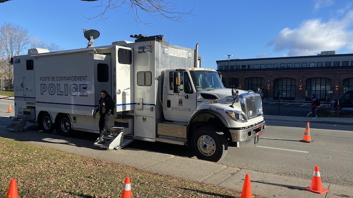 Un poste de commandement de la police de Québec, entouré de cône orange, dans un stationnement.