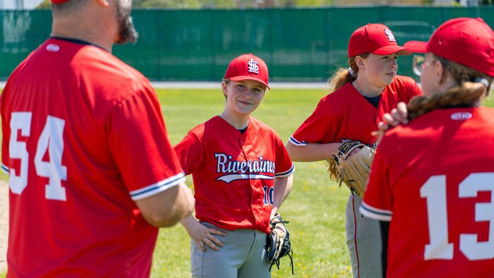 Des personnes en habits sportifs se tiennent debout sur un terrain de baseball.