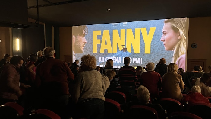 Des spectateurs dans une salle de cinéma debouts