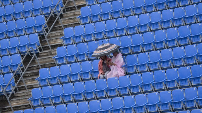 Des amateurs de tennis bravent la pluie pour observer Félix Auger-Aliassime à l'entraînement.