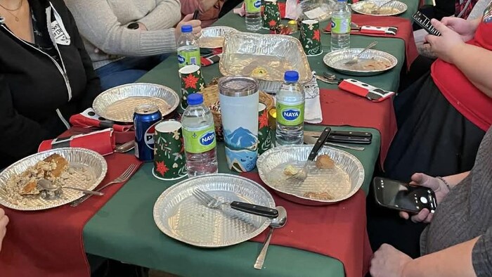 Des personnes assises autour d'une table mangent ensemble ce qu'elles ont cuisiné.