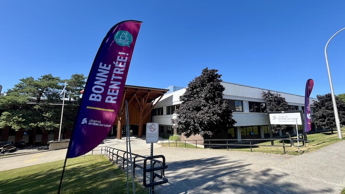 Une bannière souhaitant une bonne rentrée flotte au vent devant l'entrée principale d'un bâtiment.