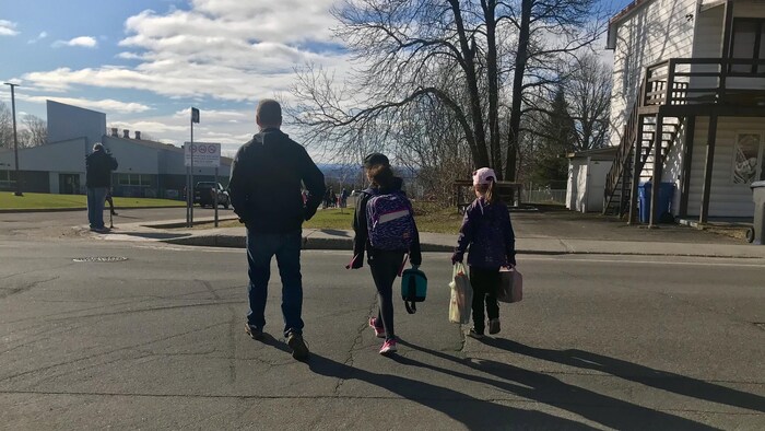 Un monsieur raccompagne ses deux enfants à l'école lundi matin.