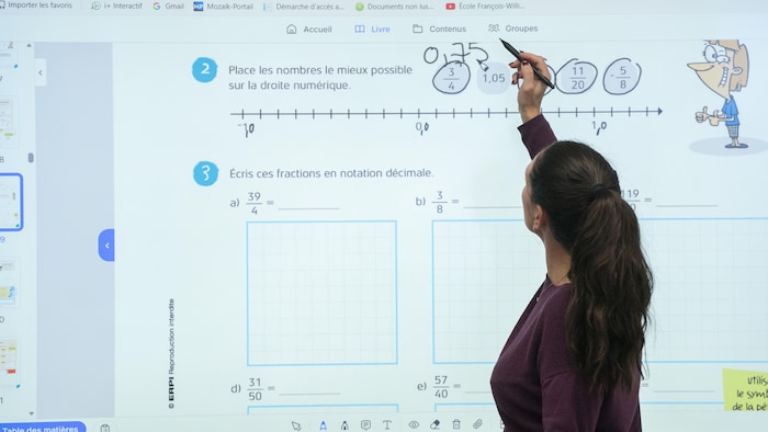 Une enseignante écrit au tableau.