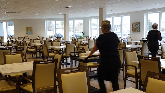 Des employés s'affairent dans une salle à manger vide.