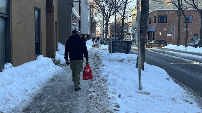 Des piétons sur un trottoir mal déneigé.