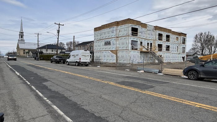 Un immeuble en construction sur le bord d'une rue principale d'un cœur villageois.
