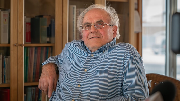 Gaston Roy, 78 ans, devant une bibliothèque.