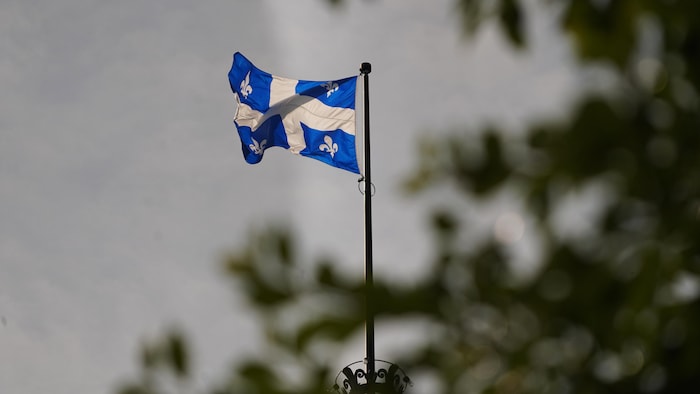 Le drapeau du Québec flotte au-dessus de l'hôtel du Parlement.
