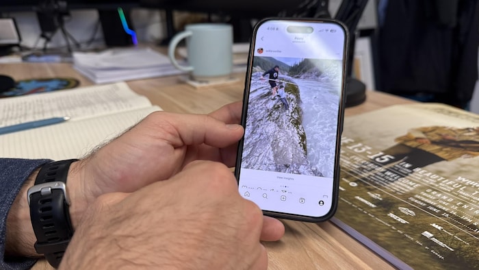 Des mains montrent une photo de pêche sur un cellulaire.