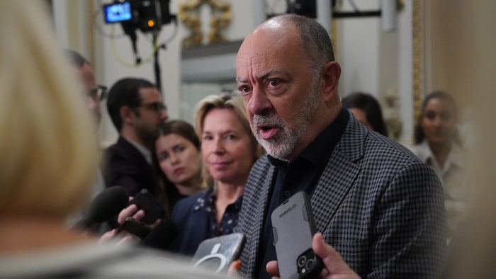 Un homme parle au micro dans une mêlée de presse.