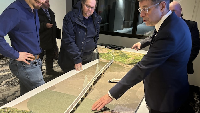 Eric Duhaime montre une maquette à deux partisans.