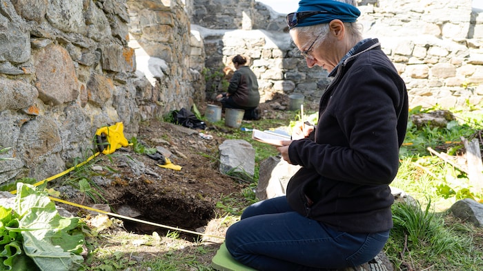 Hélène Dupont-Hébert examine un trou sur un site archéologique.