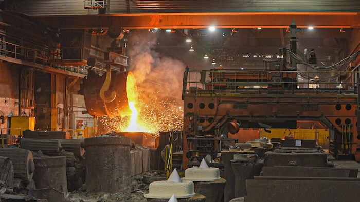 Des cuves d'où sortent des flammes, dans les Forges de Sorel.
