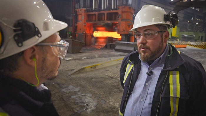 Louis-Philippe Lapierre-Boire parle avec notre journaliste dans l'aciérie. Tous deux portent un casque et des lunettes de protection.