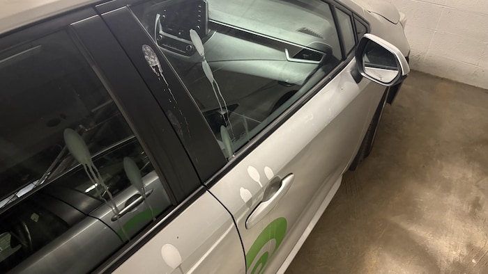 Un véhicule Communauto avec des coulisses grises et des marques de corrosion.