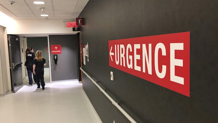Des employés circulent dans un corridor où il est inscrit «urgence».