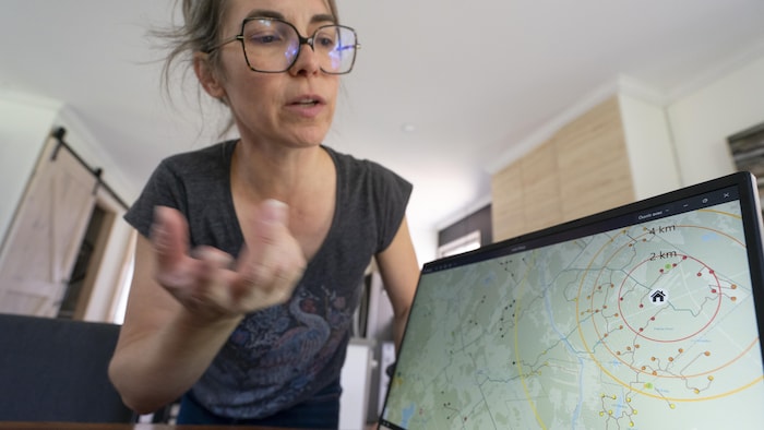 Véronique devant son ordinateur pour nous montrer où seront situées les éoliennes par rapport à sa maison.