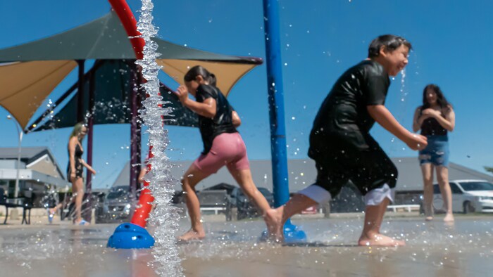 Des enfants s'amusent dans des jeux d'eau extérieurs.