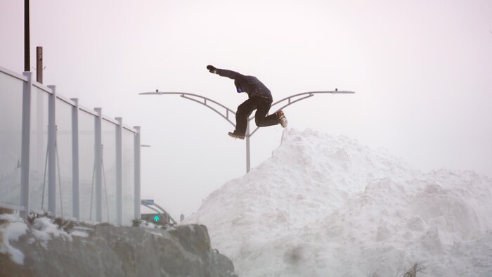 Un jeune saute sur une montagne de neige à Rimouski.