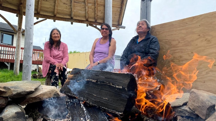 Trois femmes assises autour d'un feu. 