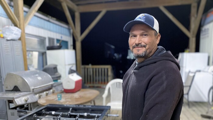 José Luis Zaragoza sourit à la caméra à côté d'un jeu de football de table. Il est un travailleur agricole d'expérience. Il est ici dans une ferme à Langley, Colombie-Britannique. 