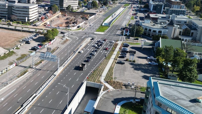 Vue aérienne d'un boulevard urbain à plusieurs voies où circulent des véhicules près de l'accès à un tunnel routier.