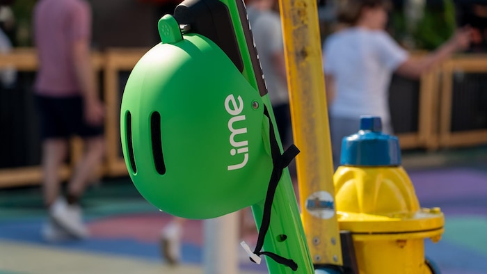 Un casque accroché à une trotinette Lime.