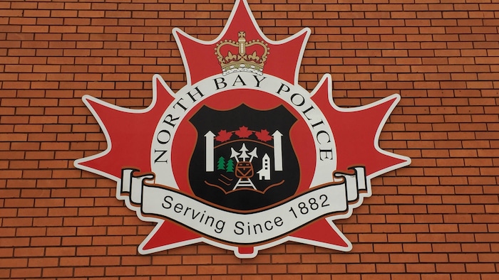 L'enseigne du Service de police de North Bay sur un mur de brique.