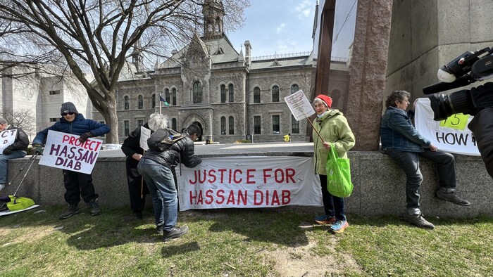 Deux personnes semblent accrocher une banderole sur laquelle il est écrit, en anglais, « Justice pour Hassan Diab ».