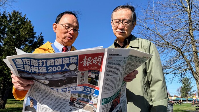 Victor Ho et Bill Chu regardent un journal.
