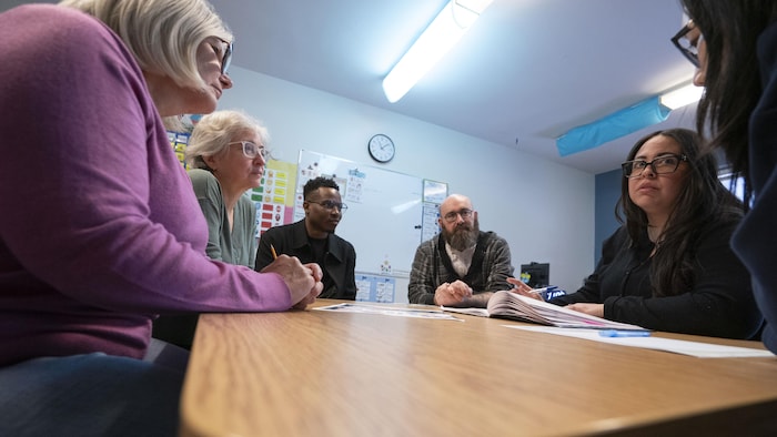 Six adultes réunis autour d'une table.